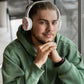 Man wearing white headphones and a green hoodie sitting at a table.